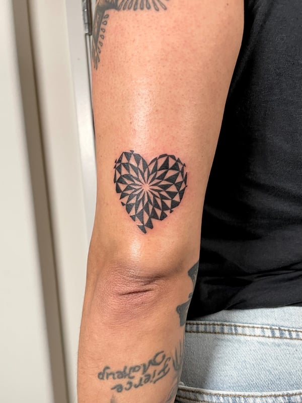 A bold black and grey geometric heart tattoo on the arm, featuring intricate sacred geometry patterns — by Brian Kies, los angeles