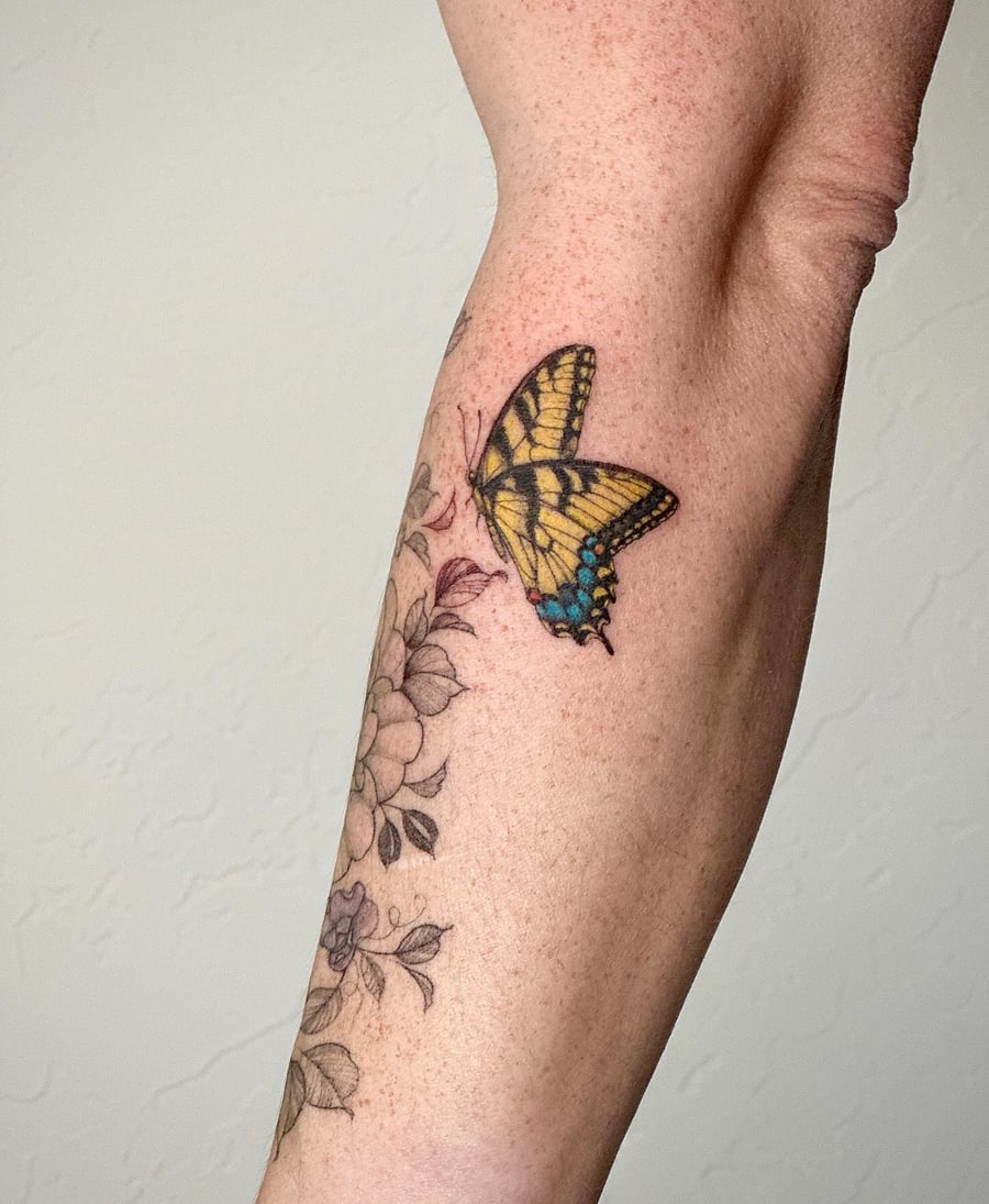 A realistic butterfly and floral tattoo on the forearm, featuring vibrant colors and delicate details — by Melanie Benoit, los angeles