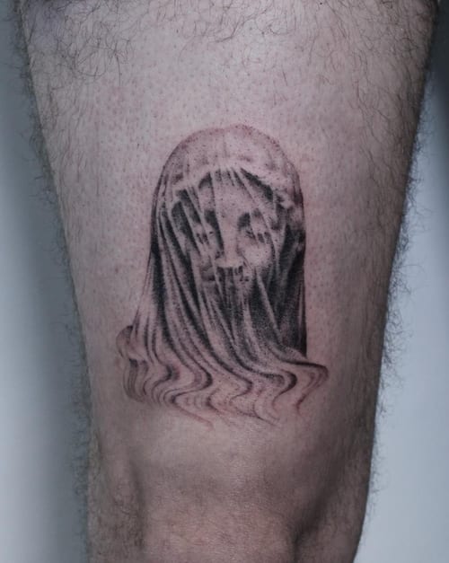 A black and grey realism tattoo of a veiled face on the thigh, featuring detailed shading and a mysterious expression — by Jian Liang, los angeles