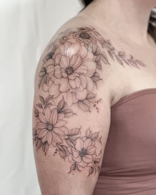 A delicate black and grey floral arrangement on the shoulder featuring fine line work and detailed flowers — by Melanie Benoit, los angeles