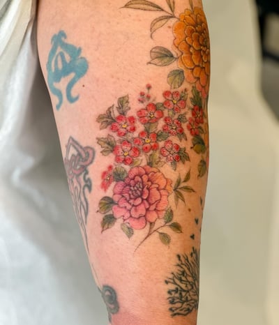 A colorful floral bouquet tattoo on the arm featuring traditional style flowers with delicate and romantic details — by Melanie Benoit, los angeles
