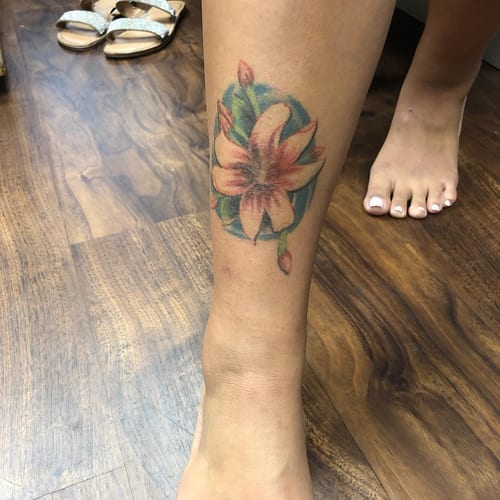 A colorful watercolor flower tattoo on the calf, featuring delicate floral design and soft hues — by Sandra Price, los angeles