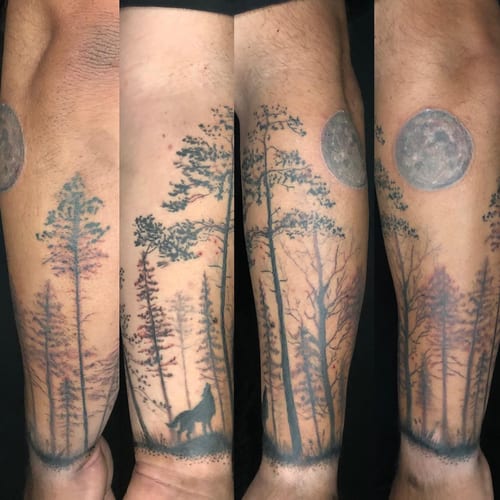 A black and grey tattoo of a wolf howling at the moon surrounded by a forest on the forearm — by Sandra Price, los angeles
