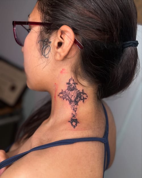 An ornate blackwork cross tattoo on the neck with intricate detailing — by zealous, los angeles