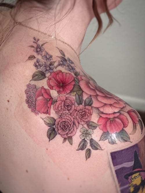 A colorful floral bouquet tattoo on the shoulder featuring roses and other flowers in a delicate and romantic style — by Melanie Benoit, los angeles