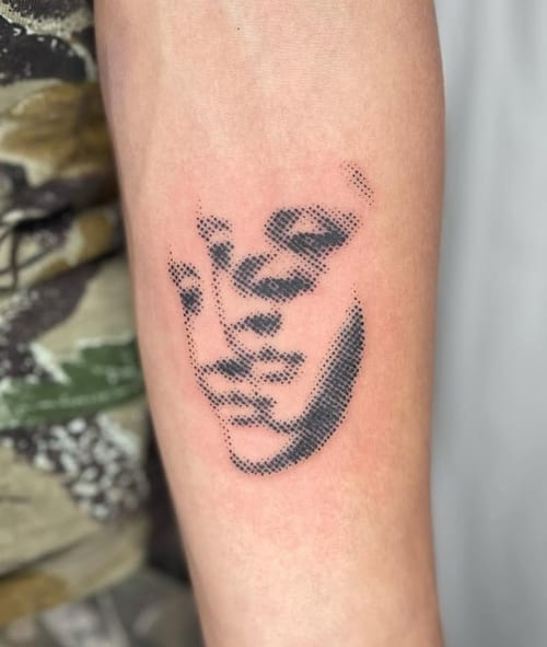 A minimalist dotwork tattoo of a face on the forearm, using black ink with a simple and abstract design — by Level tattoo, los angeles