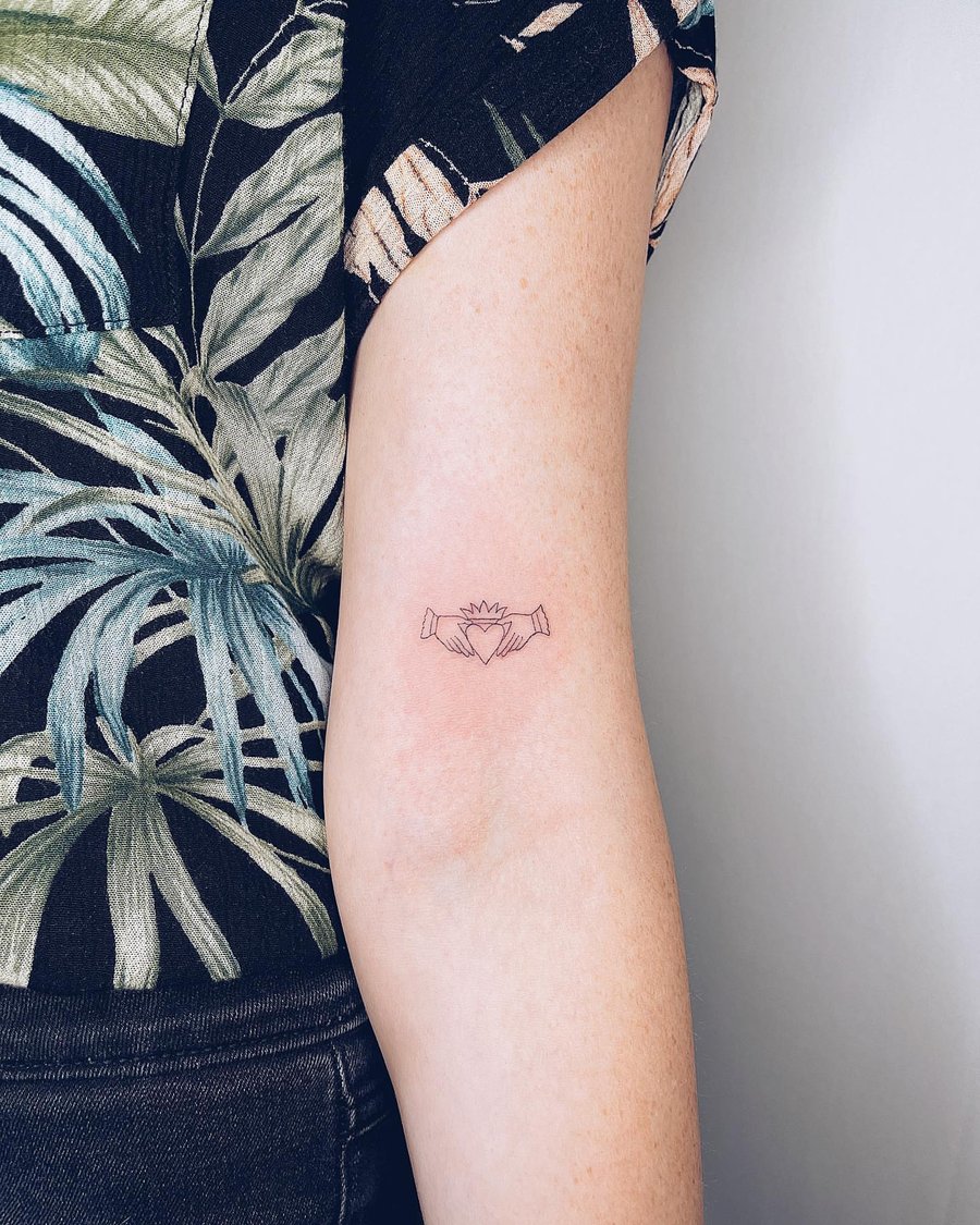 A minimalist linework claddagh symbol tattoo on the forearm, featuring a heart and crown — by Level tattoo, los angeles