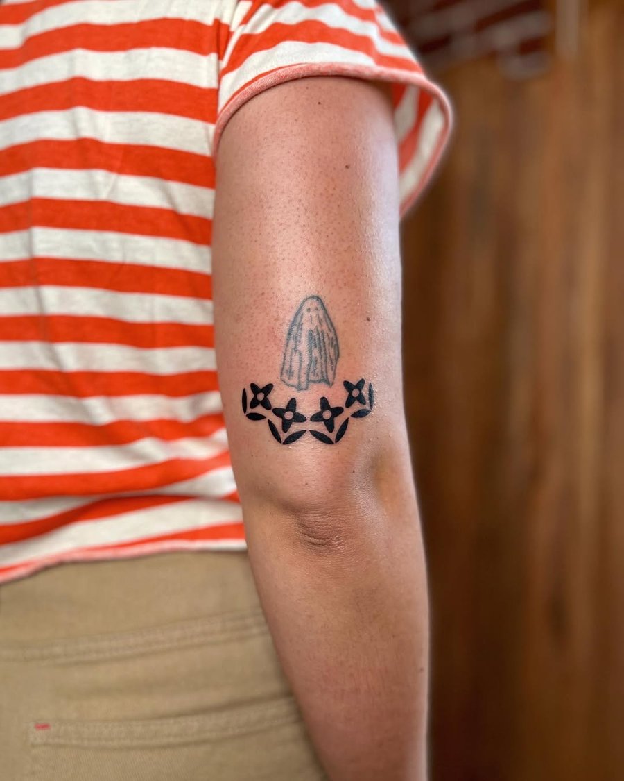 A minimalist black and grey tattoo of praying hands with flowers on the arm — by Dylan Aiello, los angeles