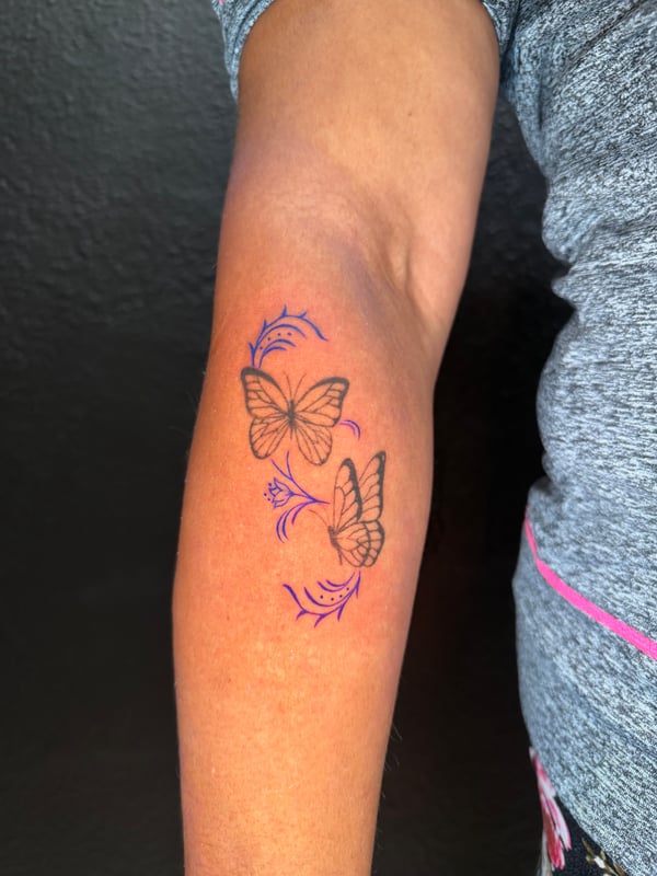 A delicate fine line butterfly tattoo on the forearm with minimalistic design elements and subtle color accents — by Kiera Garvin, los angeles