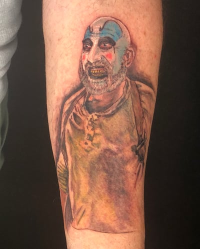 A realistic and colorful clown portrait tattoo on the forearm, featuring bold colors and detailed facial features — by Sandra Price, los angeles