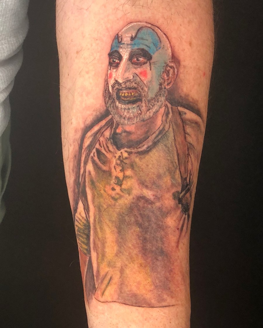 A realistic and colorful clown portrait tattoo on the forearm, featuring bold colors and detailed facial features — by Sandra Price, los angeles