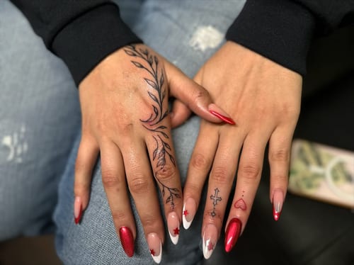 Delicate blackwork finger tattoos featuring leaves and symbols on the hand — by Maddie Ramirez, los angeles