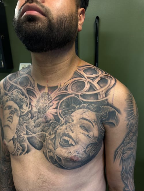A bold black and grey woman's portrait on the chest with detailed facial features and ornate design elements — by Humilde tattoos, los angeles