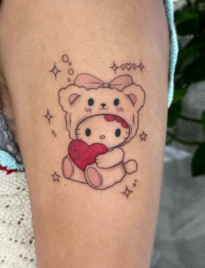 A cute Kawaii style tattoo of a character resembling a cat holding a heart, with linework and soft colors on the thigh — by otaybeatdown, los angeles