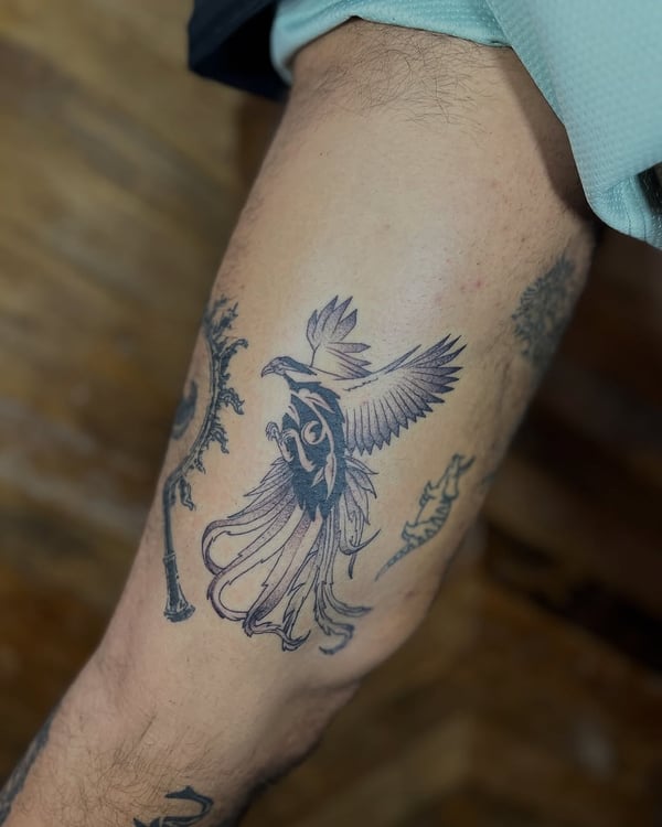 A bold black and grey tribal phoenix tattoo on the leg with intricate feather details — by Dylan Aiello, los angeles
