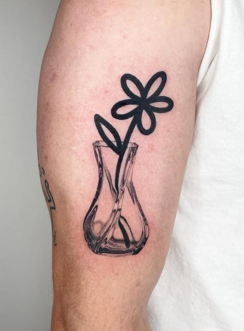 A minimalist black and grey tattoo of a simple flower in a vase on the upper arm, featuring clean linework — by Level tattoo, los angeles