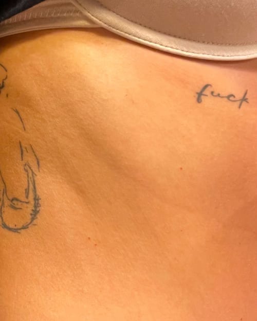 A minimal black script lettering tattoo on the rib with simple linework — by Melanie Benoit, los angeles