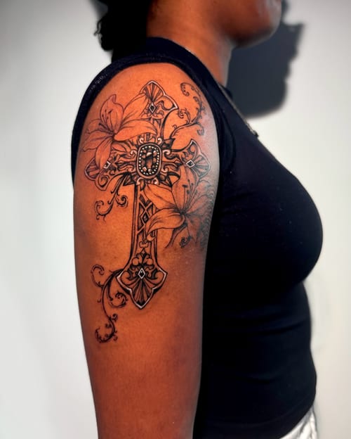An ornate black and grey cross with floral elements on the upper arm, featuring intricate detailing and bold lines — by Shelby Bianco, los angeles