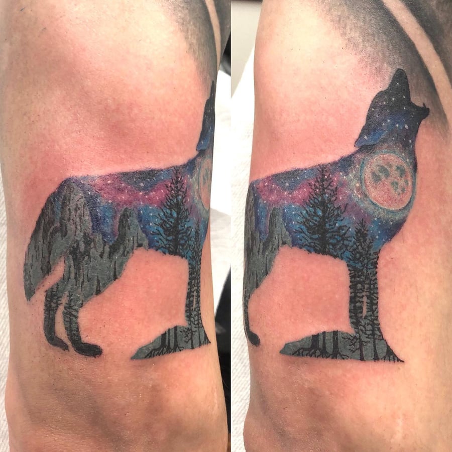 A colorful silhouette of a howling wolf with a landscape scene on the upper arm, featuring a moon and trees — by Sandra Price, los angeles