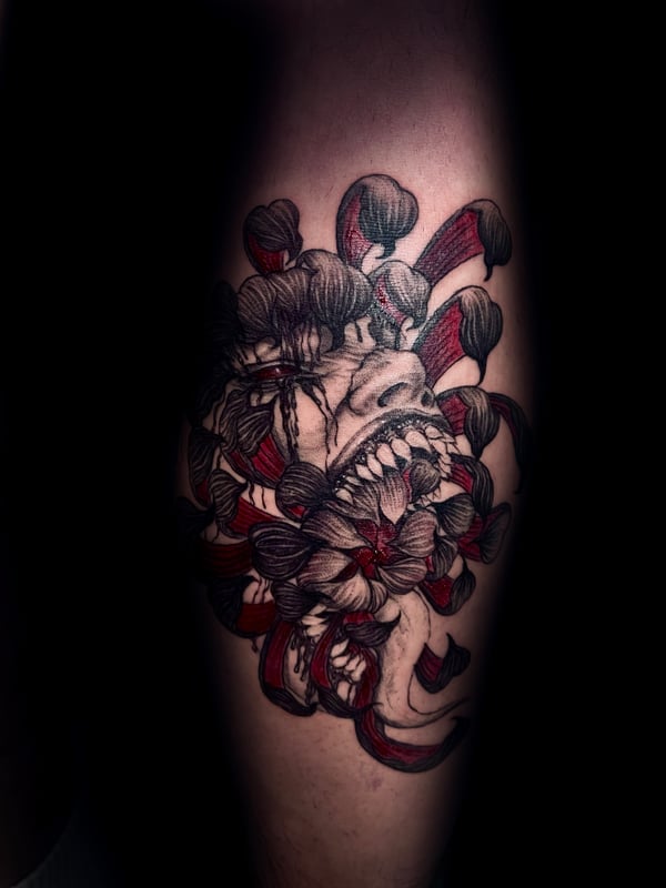 A Neo-Traditional tattoo on the leg featuring a skull intertwined with red and black flowers, combining bold outlines with illustrative details — by zitronxus, los angeles