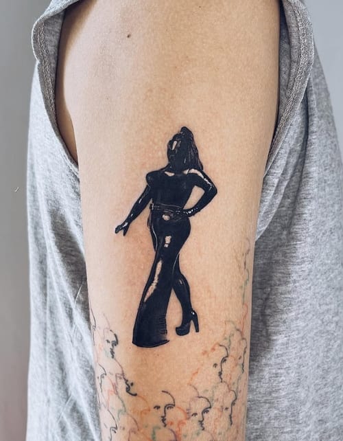 A black silhouette tattoo of a woman in a confident pose on the upper arm, featuring bold black ink — by Level tattoo, los angeles