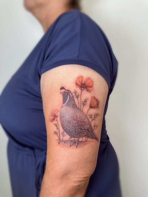 A realistic quail with flowers tattoo on the upper arm, featuring detailed shading and delicate floral elements — by Melanie Benoit, los angeles
