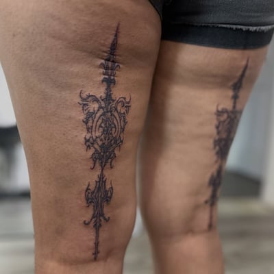 An ornate black and grey ornamental dagger tattoo on the thigh — by Maddie Ramirez, los angeles