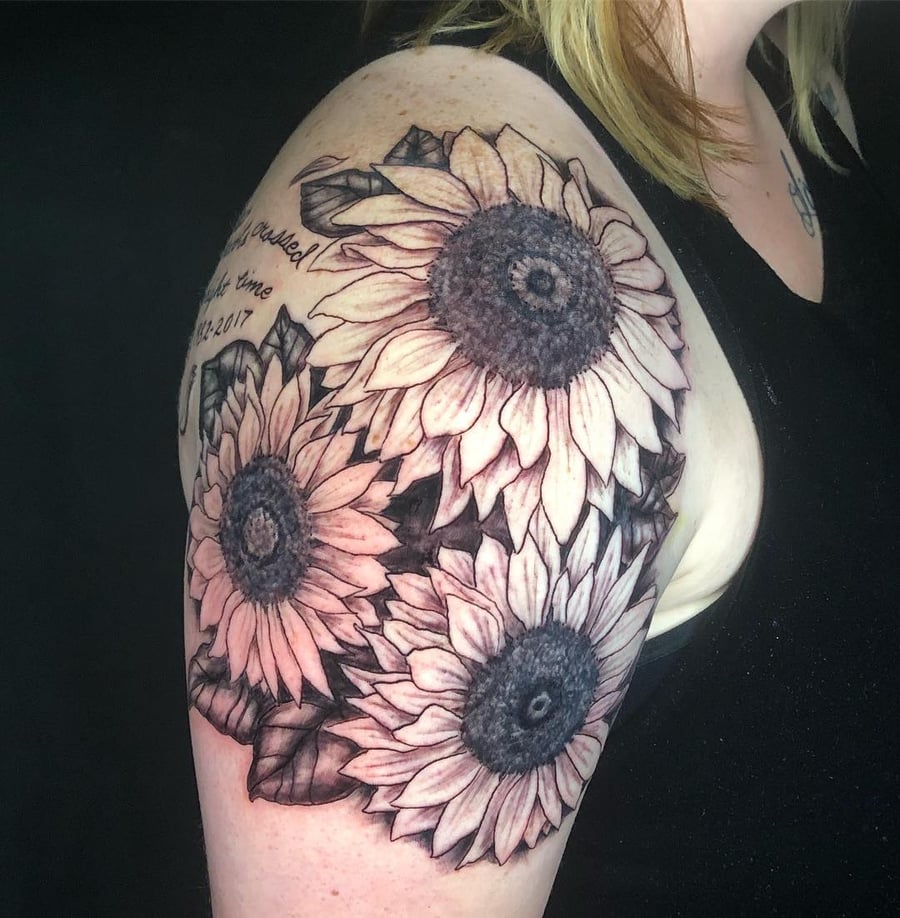 A black and grey realistic sunflower tattoo on the upper arm with delicate shading and detail — by Sandra Price, los angeles