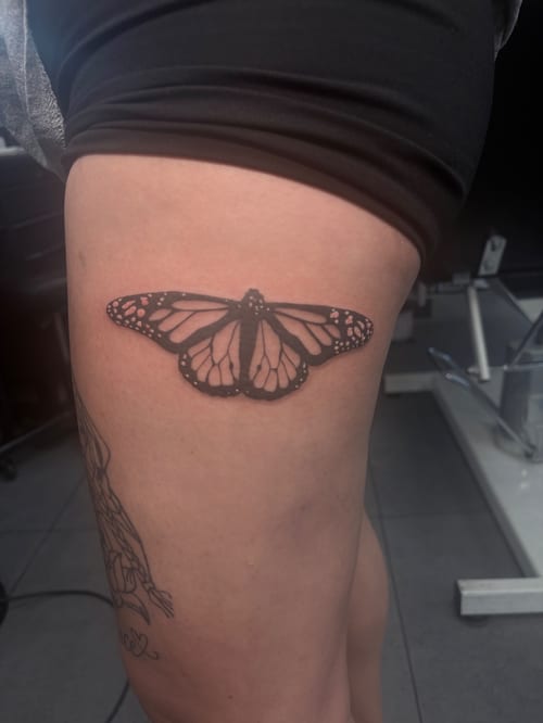 A minimalist black and grey butterfly tattoo on the thigh, featuring clean lines and simple shading — by Hannah , los angeles