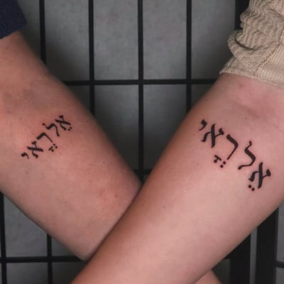 Matching black ink Hebrew script tattoos on the forearm with a minimalist style — by Miguel ANGELO, los angeles