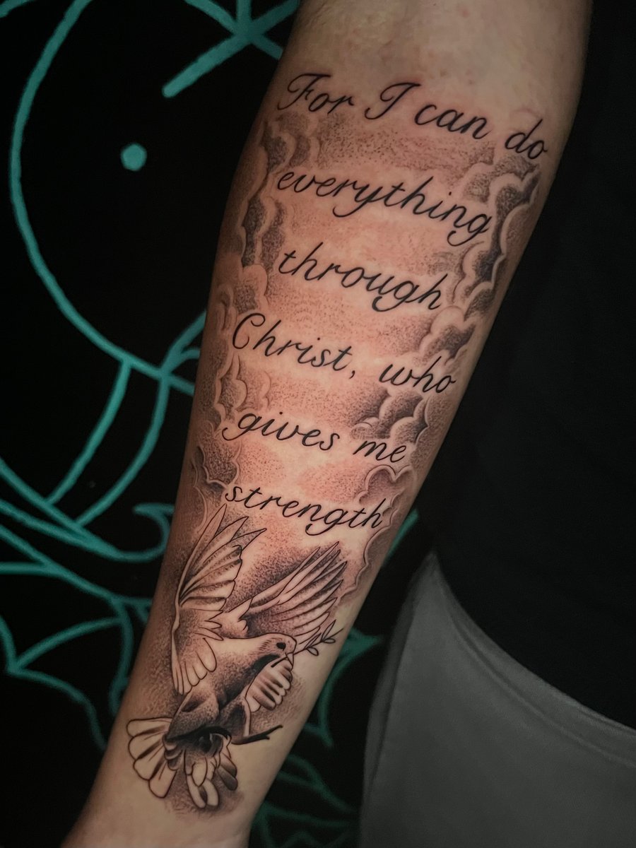 A black and grey forearm tattoo featuring a script quote with a detailed bird and cloud background — by Josue Bravo, los angeles