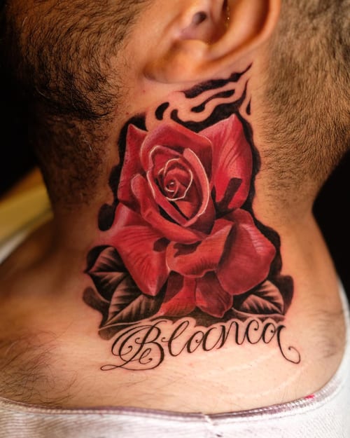 A bold and realistic red rose tattoo on the neck with script lettering of a name beneath it — by Johnny Ayala, los angeles