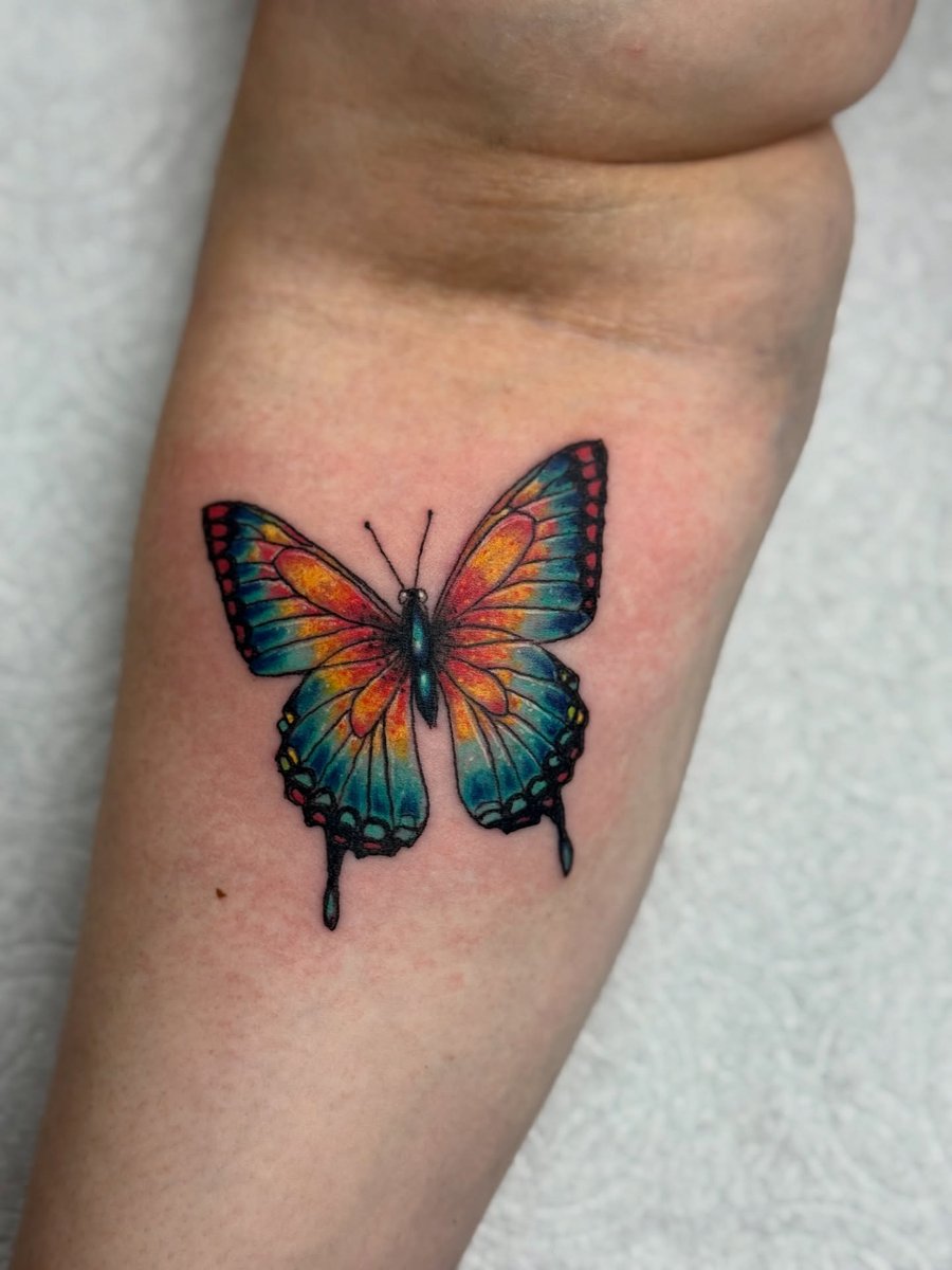 A vibrant and colorful butterfly tattoo on the forearm with an illustrative style — by Sandra Price, los angeles