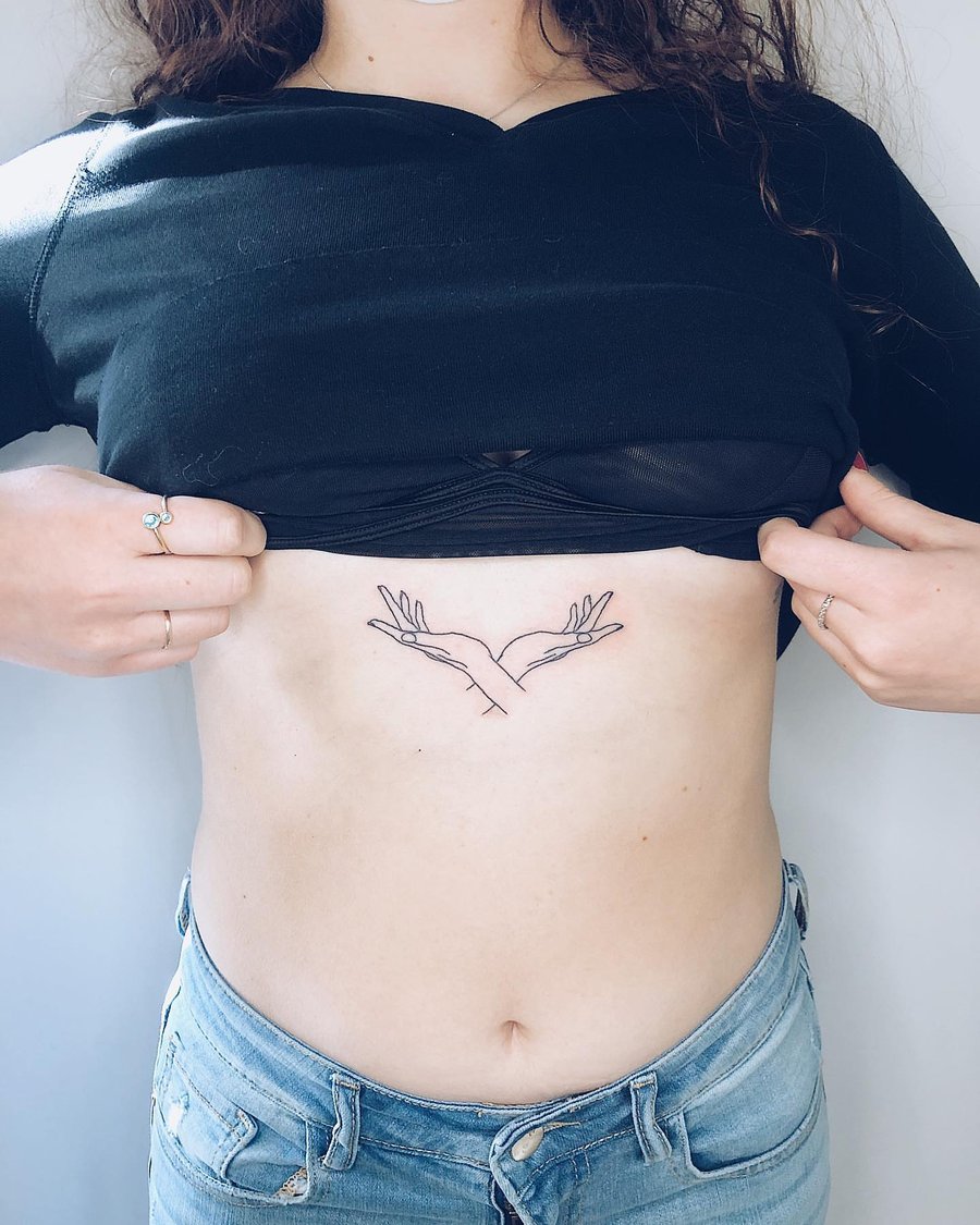 A minimalist linework tattoo of hands forming a heart shape on the rib area — by Level tattoo, los angeles