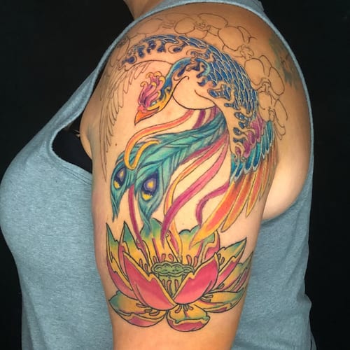 A vibrant color tattoo of a phoenix and lotus on the upper arm, featuring bold Japanese style and intricate details — by Sandra Price, los angeles