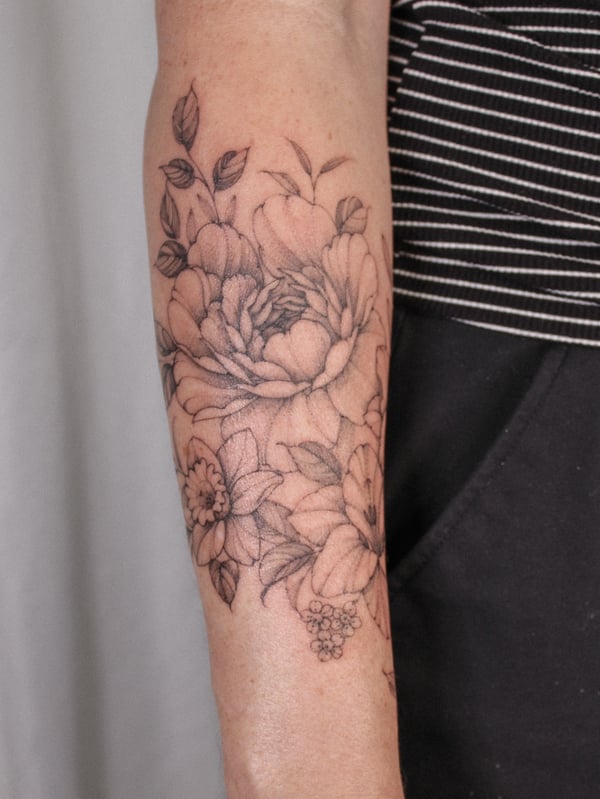 A delicate black and grey floral bouquet tattoo on the forearm, featuring fine line work and clean detailing — by Melanie Benoit, los angeles