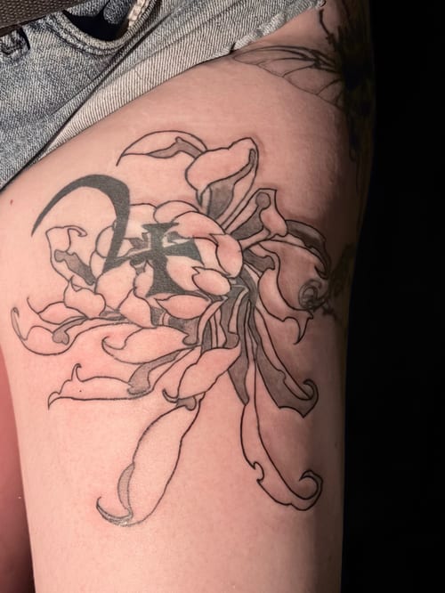 A black and grey linework tattoo of a flower on the thigh, featuring flowing petals and bold outlines — by Hannah , los angeles