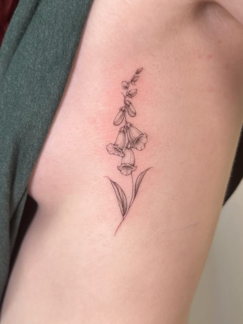 A delicate fine line flower tattoo on the rib, featuring a minimalist black and grey design — by Melanie Benoit, los angeles