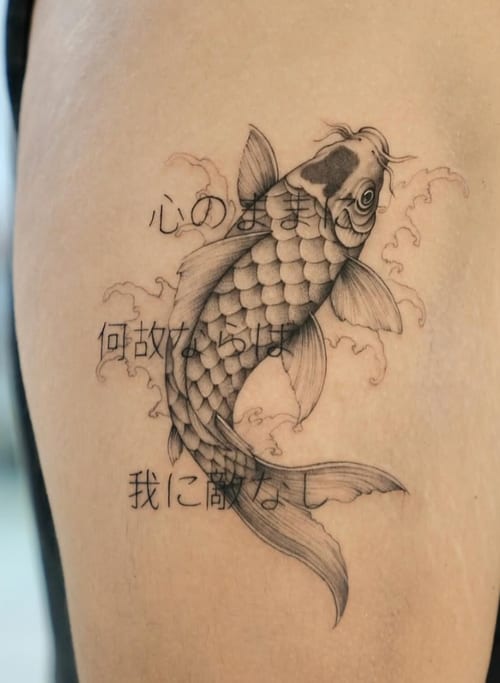 A black and grey fine line tattoo of a koi fish with Japanese script on the upper arm, featuring delicate line work and subtle shading — by otaybeatdown, los angeles