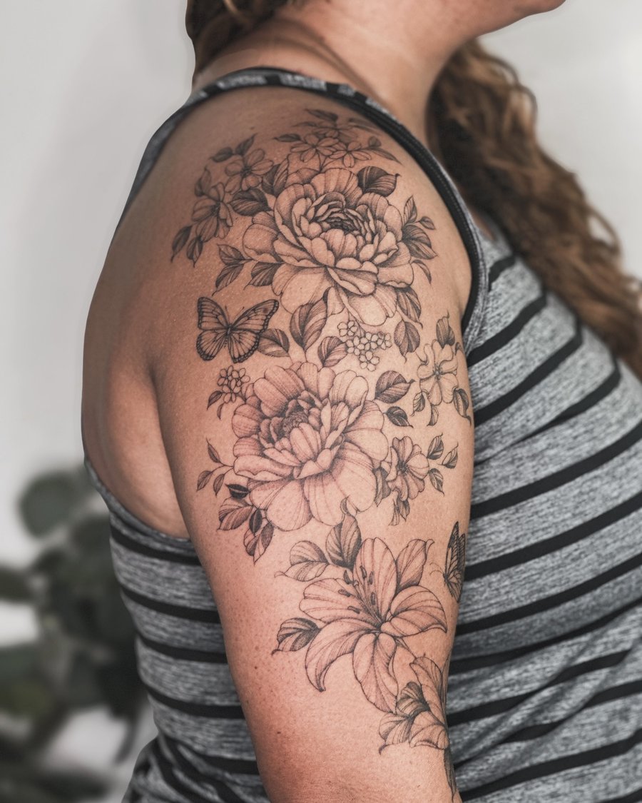 A delicate black and grey floral bouquet with a butterfly on the upper arm, featuring realistic shading and intricate details — by Melanie Benoit, los angeles