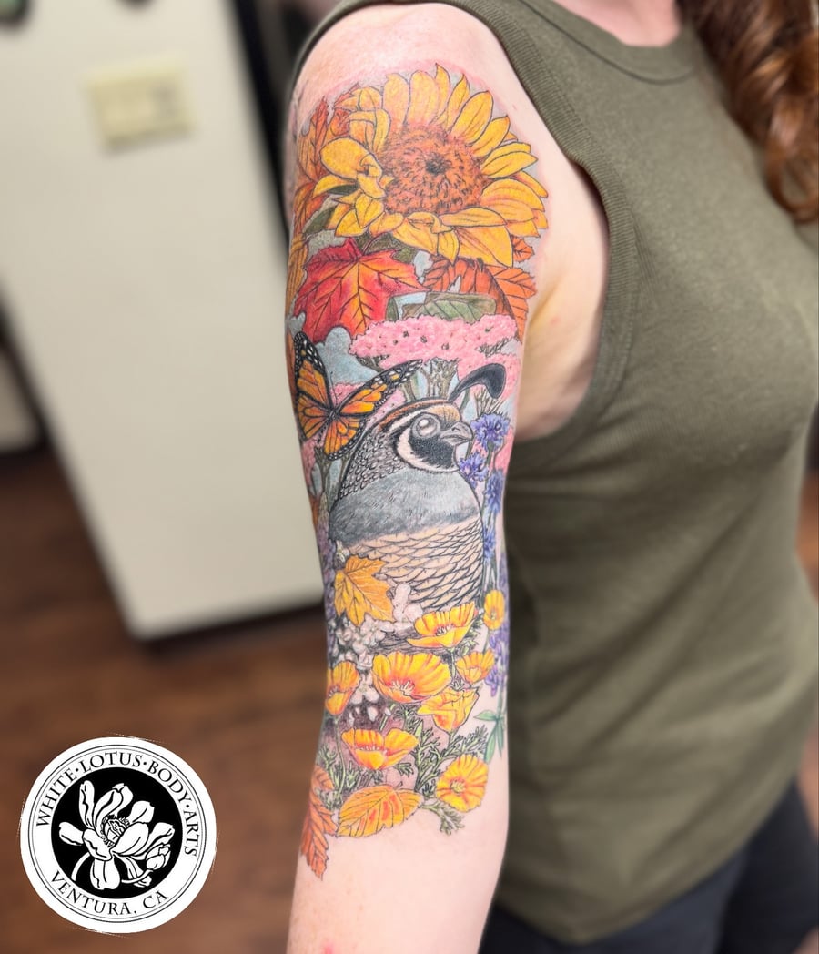 A colorful tattoo of a quail surrounded by flowers and a butterfly on the upper arm, done in an illustrative style — by Sandra Price, los angeles