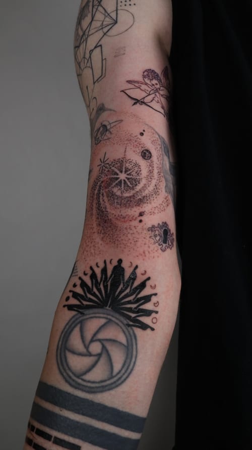 A black and grey abstract tattoo on the upper arm featuring dotwork and geometric patterns with celestial elements — by Vince Espinoza, los angeles