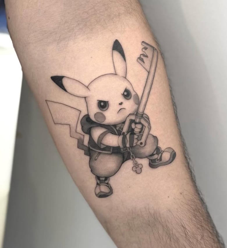 A black and grey tattoo of Pikachu holding a sword on the forearm, featuring bold outlines and a cartoonish style — by otaybeatdown, los angeles