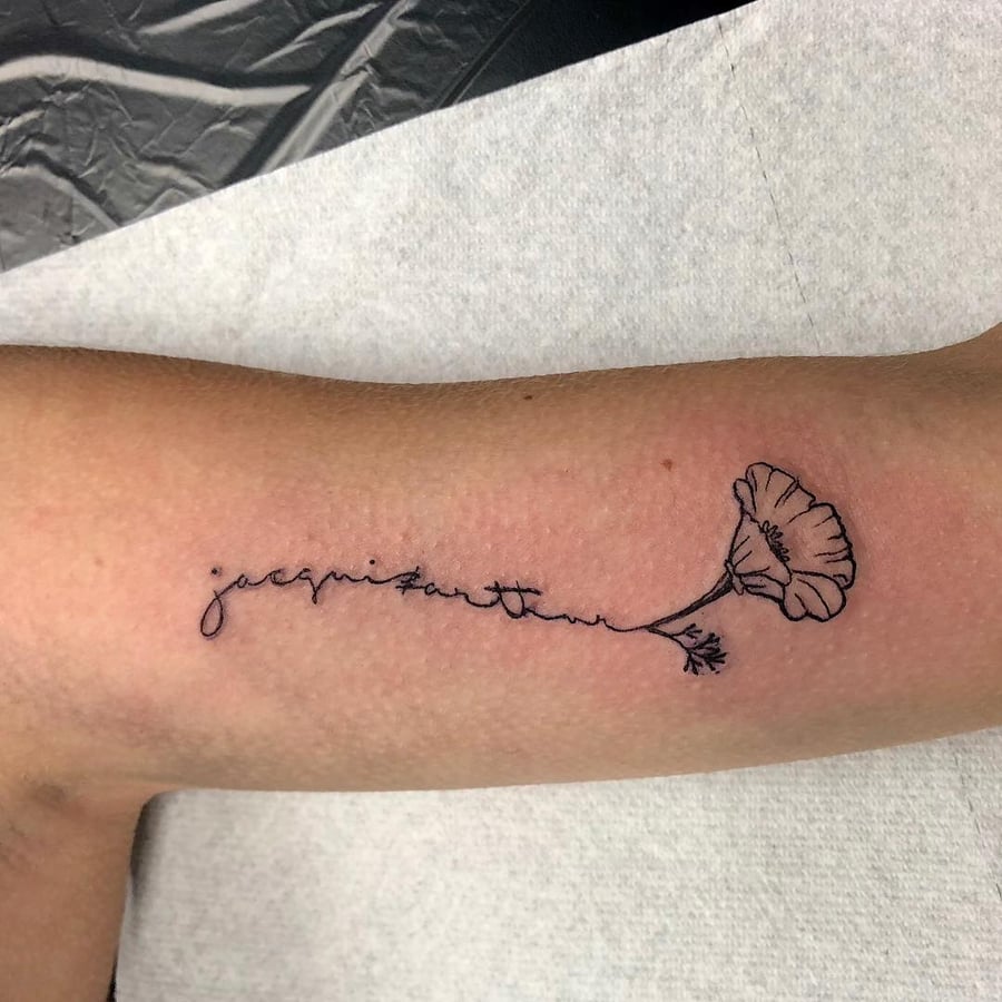 A delicate fine line tattoo of a flower with script on the forearm, done in black ink — by Sandra Price, los angeles