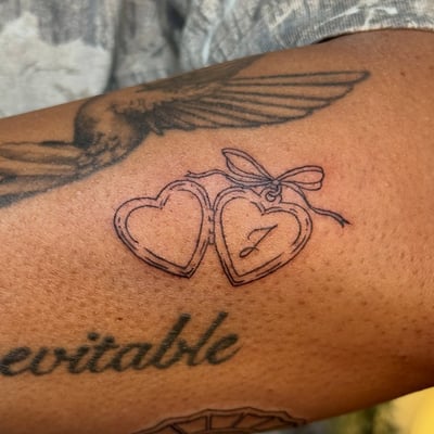 A delicate fine line tattoo of heart lockets on the forearm, done in black and grey ink — by NJ TATTOOZ, los angeles