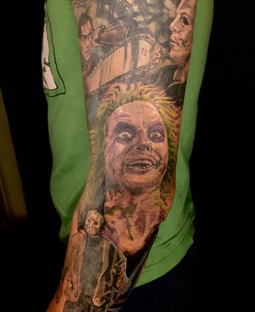 A colorful tattoo sleeve featuring realistic portraits of horror movie characters on the forearm — by Sandra Price, los angeles