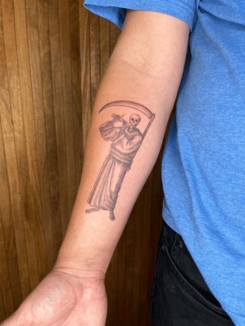 A black and grey linework tattoo of a skeleton holding a scythe on the forearm, featuring detailed line art and shading — by Dylan Aiello, los angeles
