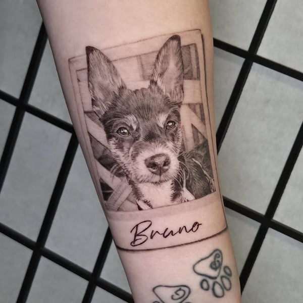 A realistic black and grey dog portrait tattoo on the forearm, featuring detailed shading and lifelike texture — by Miguel ANGELO, temecula, ca