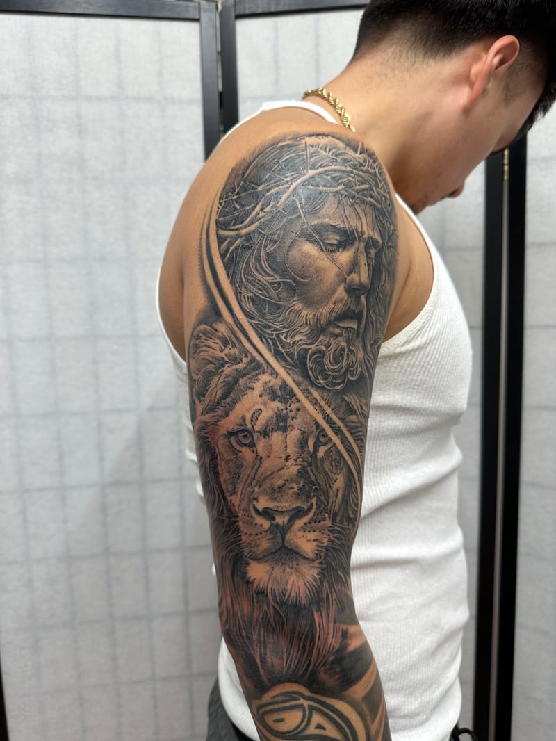 black and grey realism full sleeve tattoo of Christ in a crown of thorns above a lion by Humilde, a black and grey realism tattoo artist in mid-wilshire, los angeles