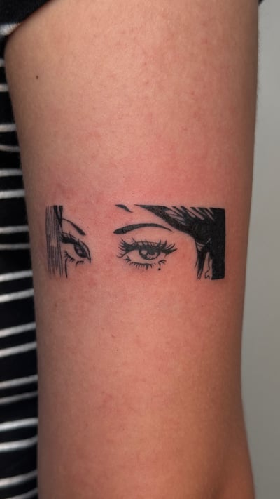 A minimalist black and grey tattoo of a pair of eyes with fine linework on the upper arm — by NJ TATTOOZ, los angeles